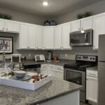 Open kitchen with white cabinets and stone island - Elements at Prairie Center