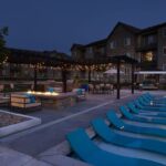 Apartment complex with lounge chairs in the water, fire pit, and seating area - Elements at Prairie Center