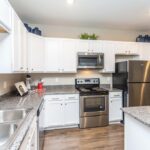 Apartment home kitchen with white cabinets and stainless steel appliances - Elements at Prairie Center