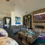 Living room-like apartment clubhouse with fireplace, couches, and arcade games - Elements at Prairie Center