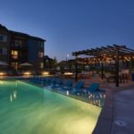 Apartment complex outdoor area with pool, pergola, and lounge chairs - Elements at Prairie Center