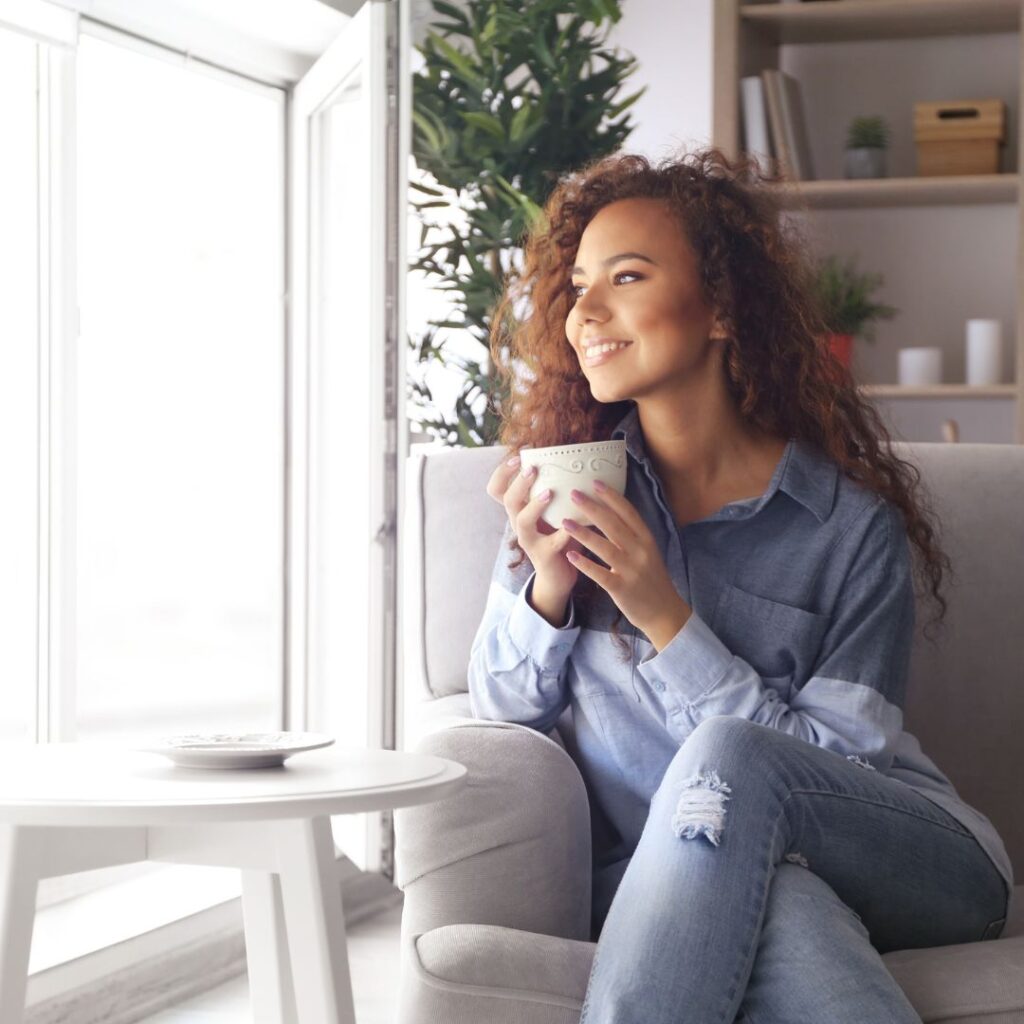 woman looking out window with a coffee mug in hand