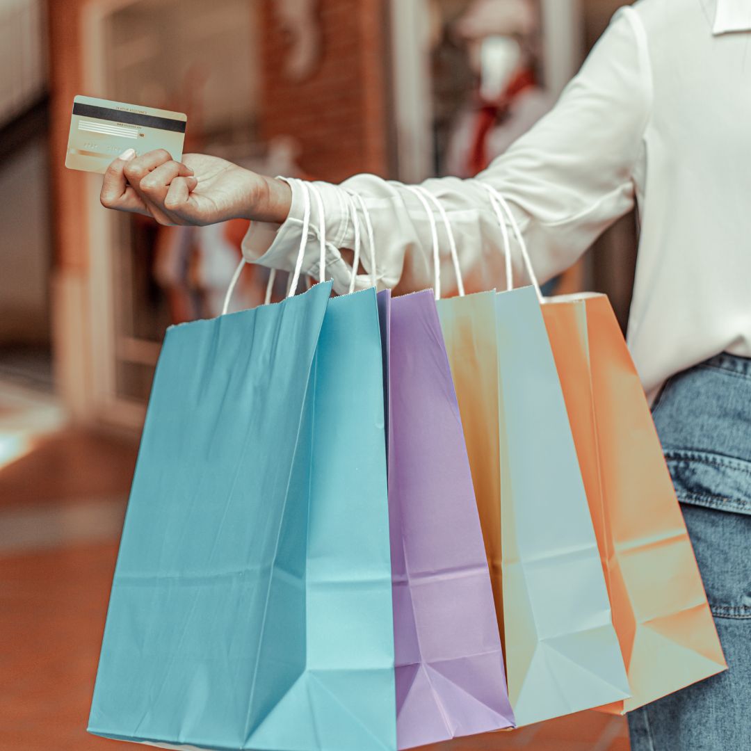 Person holding shopping bags and a credit card