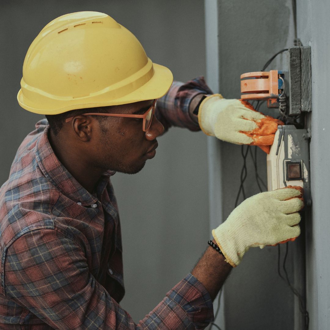 Worker fixing electrical device while wearing safety gear