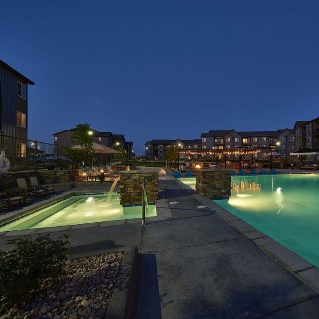community pool and hot tub lit up in the evening