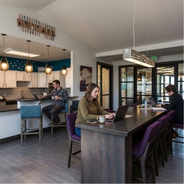 Residents working on laptops at the long high-top tables inside our modern, comfortable apartment clubhouse.